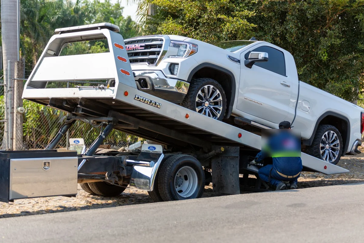 Flatbed tow truck loading a pickup truck for towing